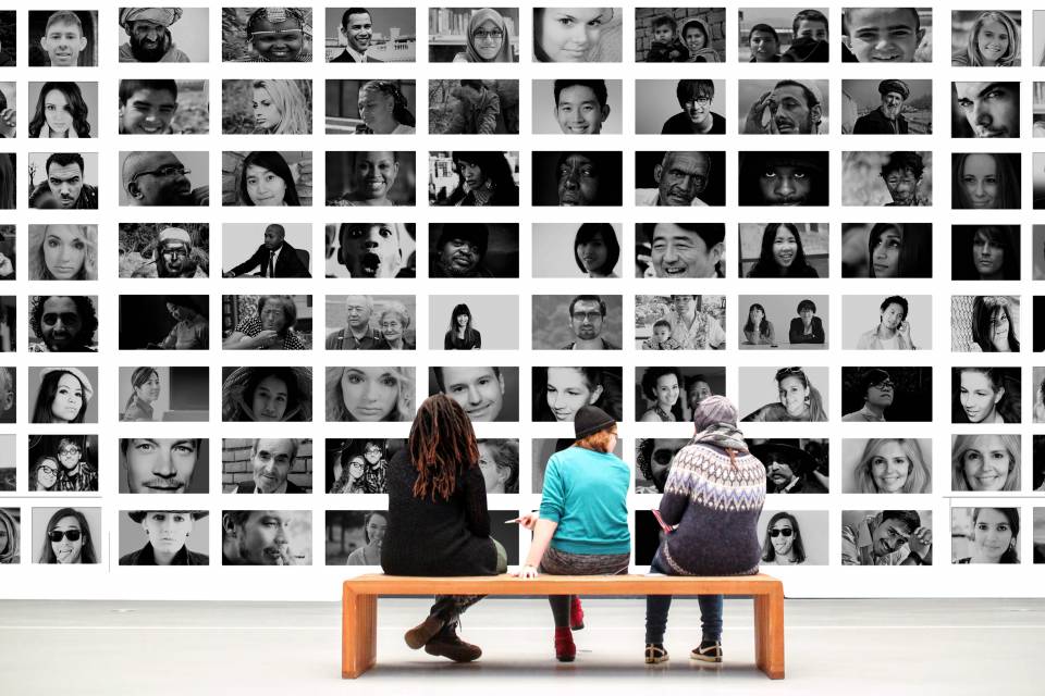 Drei Menschen auf einer Bank vor einer Foto-Ausstellung