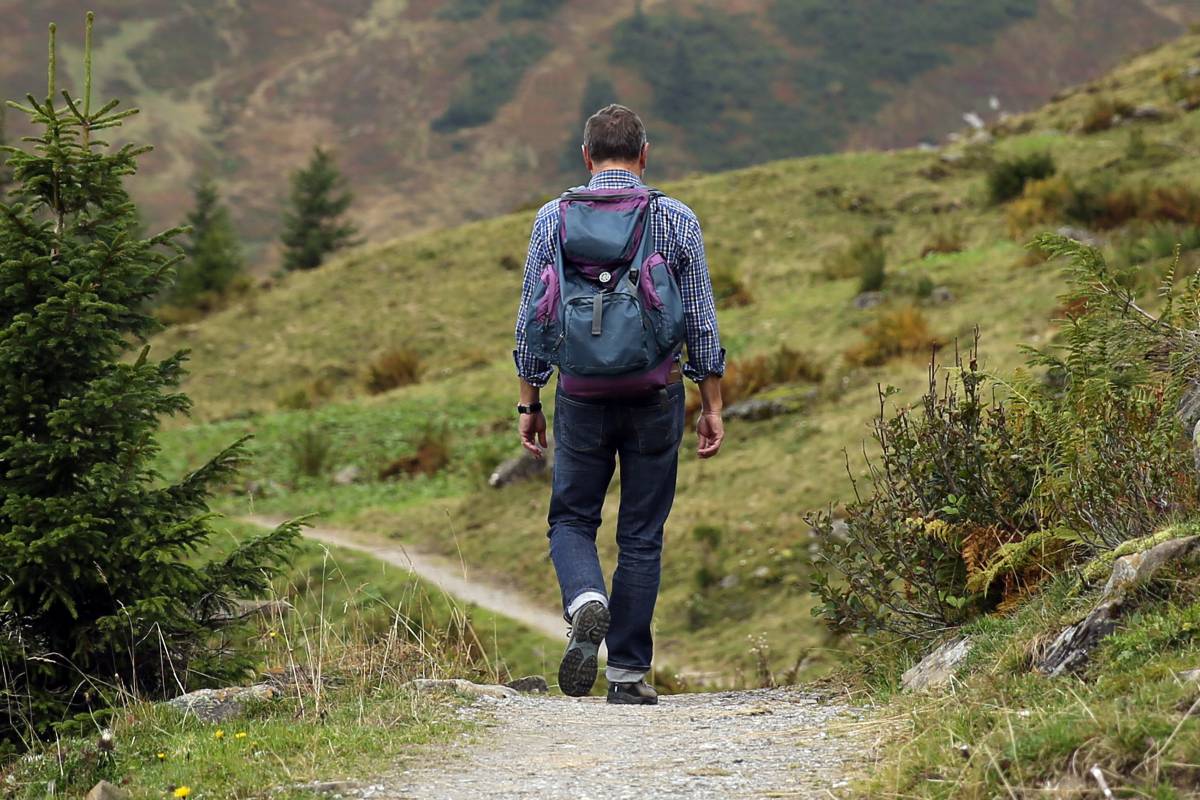 Wanderer mit Rucksack auf Schotterweg im Gebirge