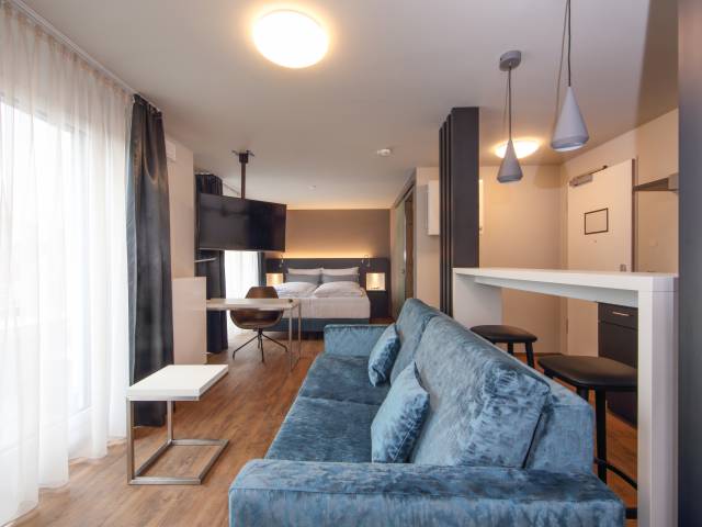 Doppelzimmer mit Bett, Sofa und Schreibtisch im Estilo Design & Lifestyle Hotel Aalen