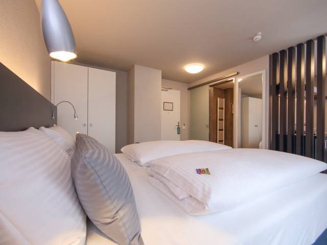 Doppelbett mit Kissen und Decken im Estilo Design & Lifestyle Hotel Aalen