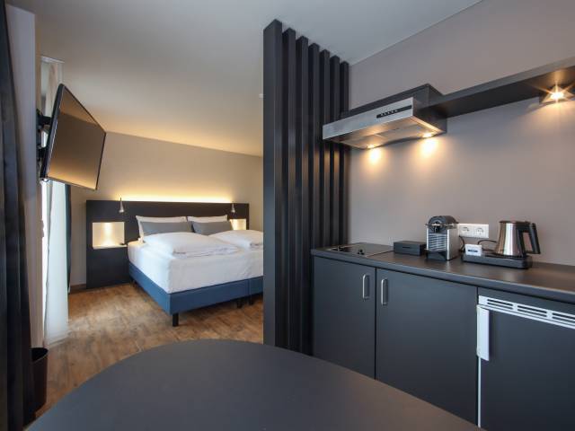 Küchenzeile und Bett im Doppelzimmer im im Estilo Design & Lifestyle Hotel Aalen