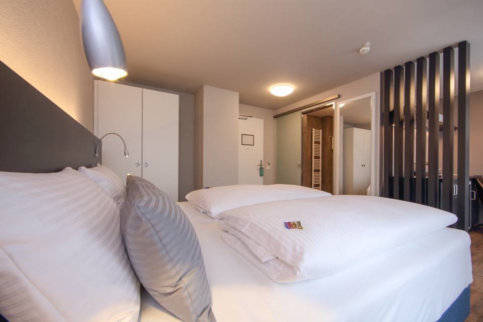 Doppelbett mit Kissen und Decken im Estilo Design & Lifestyle Hotel Aalen