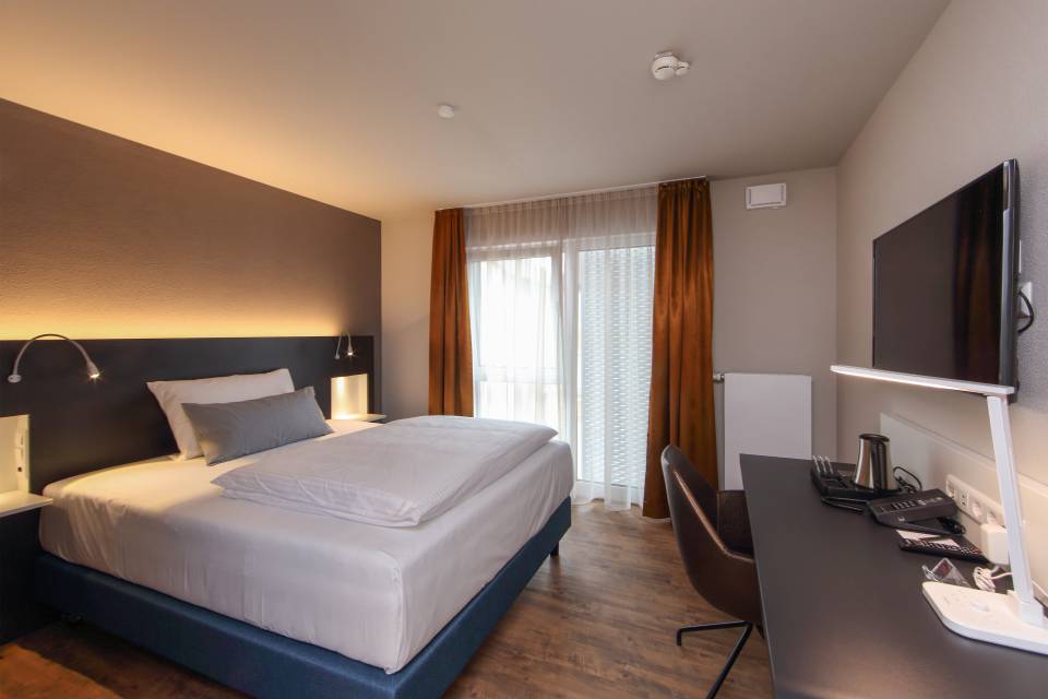 Business Zimmer mit Bett, Tisch und TV im Estilo Design & Lifestyle Hotel Aalen