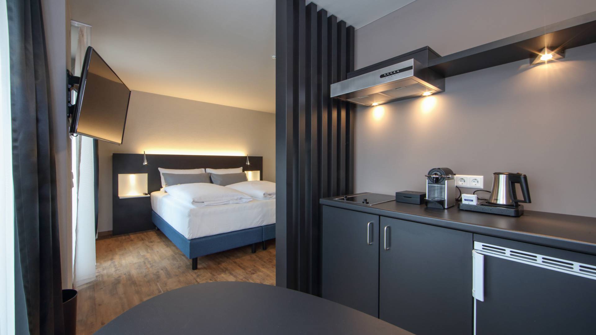 Küchenzeile und Bett im Doppelzimmer im im Estilo Design & Lifestyle Hotel Aalen